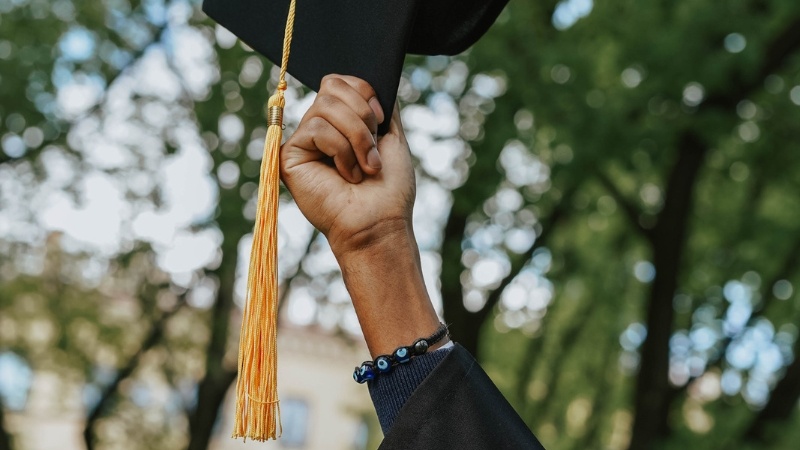 A black student holding a graduation cap.
