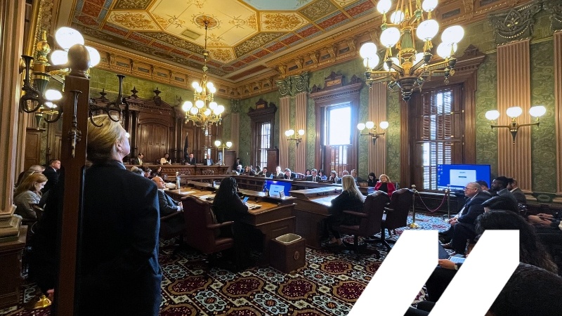 Image of Michigan Senate Chambers in session with MCAN logo in white in bottom right corner.